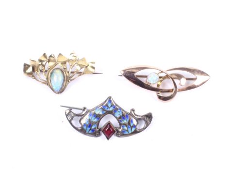 Three Edwardian brooches. Comprising; a rose gold and oval cabochon white opal 'whiplash' open scroll brooch with the mark of