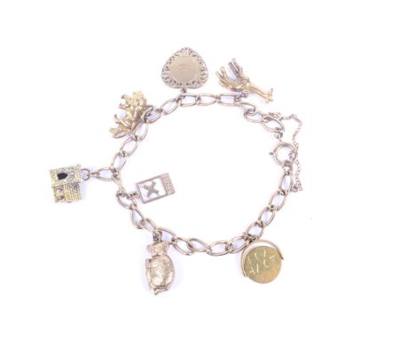 A vintage 9ct gold curb link 'charm' bracelet hung with seven charms including a koala; a church with a tower enclosing a sta
