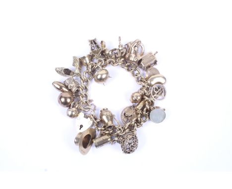 A 9ct gold curb link 'charm' bracelet on a padlock clasp with hallmarks for Birmingham 1963. Hung with 27 various charms incl