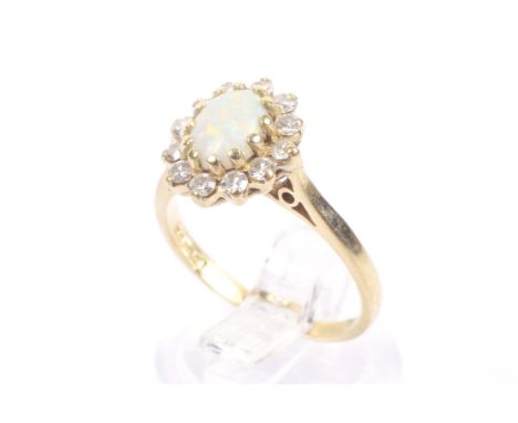 A vintage 18ct gold, opal and diamond twelve stone oval cluster ring. The oval cabochon white opal, claw set within a round b