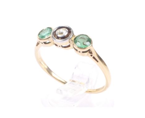 An Art Deco gold, emerald and diamond three stone ring. The central old-cut diamond collet set within an open surround and a 
