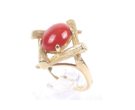 A vintage gold and red coral single stone ring. The oval cabochon red coral claw set within an abstract 'branch' surround, on