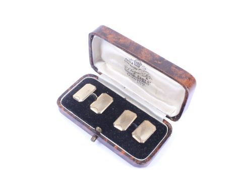 A pair of 9ct gold canted-rectangular twin-panel cufflinks. With chain inter-links, each panel engine turned with a sun-burst