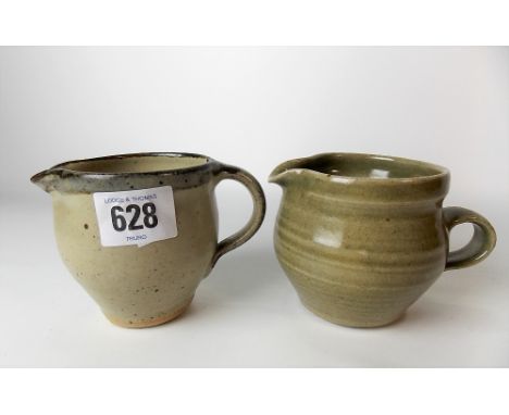 Two St Ives Leach Studio Pottery cream jugs, one with celadon glaze, the other with a mottled grey glaze, both with circular 