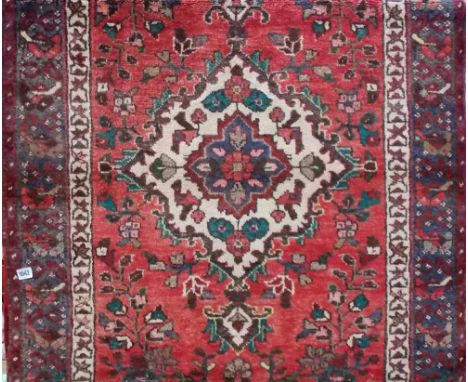 Persian wool runner with central lozenge medallion amongst foliate scrolls and borders upon a red ground, width 100cm x lengt