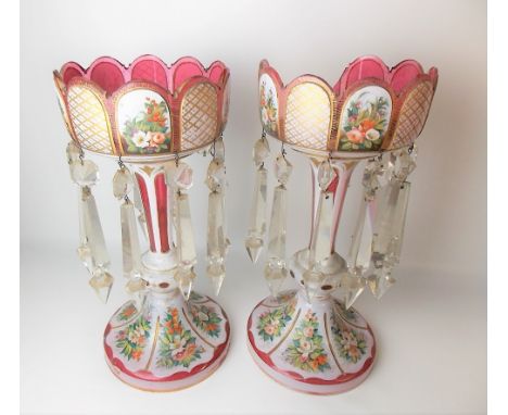 Pair of Victorian cranberry glass and white opaque table lustres with foliate painted enamel panels and gilt highlights, heig