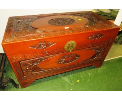 Mid 20th century Far Eastern camphorwood chest, decoratively carved to all sides, the top with dignitaries and an oval vignet