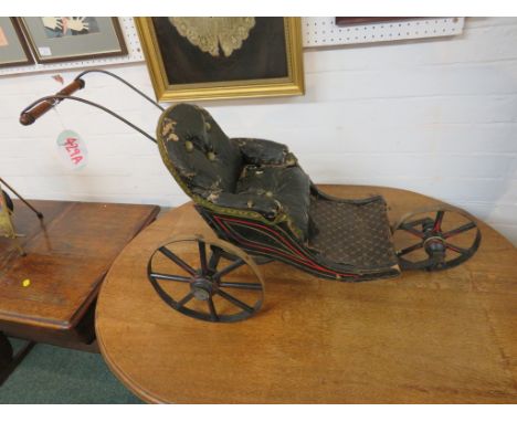 A Victorian ebonised wooden three-wheel doll's pram with overstuffed seat and button back upholstery