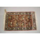 A SMALL PART SILK PERSIAN HUNTING RUG rust ground decorated with huntsmen on horseback. 3ft 3ins x