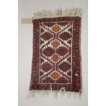 A SMALL PERSIAN MAT red ground with a geometric design. 2ft x 1ft 4ins.