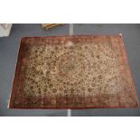 A GOOD LARGE PERSIAN SILK CARPET cream ground within a red ground border, decorated with floral