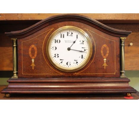 An Edwardian mahogany cased mantle clock, inlaid and with brass column mounts, the white enamel dial inscribed "Kemp and Wilc