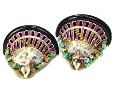 PAIR OF 19TH CENTURY CERAMIC AND WOOD WALL BRACKETS, the ebonised wood semi circular tops over pierced ceramic basket forms, 