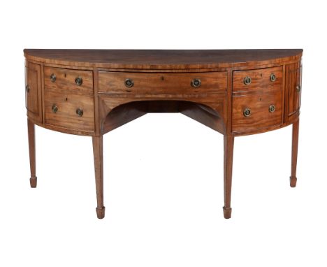 A George III mahogany sideboard, circa 1780, of semi elliptical outline, the central drawer flanked by deep drawers fronted b