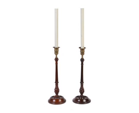 A pair of George III turned mahogany and brass mounted candlesticks, circa 1790, the beaded and foliate sconces rising from f