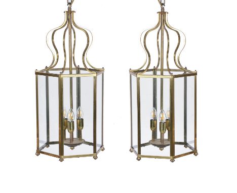 A pair of brass and glazed hexagonal hall lanterns, of recent manufacture, each frame surmounted with six serpentine ceiling 