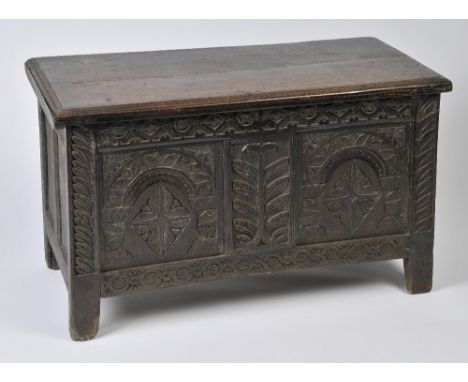 A 17TH CENTURY CARVED OAK COFFER with carved front and panel sides on square cut legs, 72cm high, 117cm wide