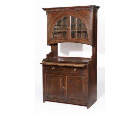 A LIBERTY & CO OAK CABINET, the top with dentil cornice over arched shaped glass doors containing two shelves, with ivorine L