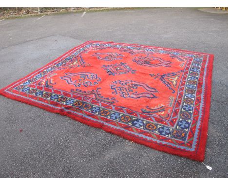 A Turkey Pattern Wool Carpet, circa 1920's, with blue and multicoloured motifs on red ground, 292 x 320cm, strengthened stitc