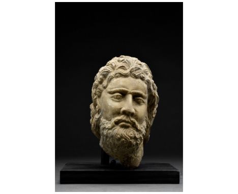 Ca. 300-100 BC. Graeco-Bactrian. A marble head of a man with a thick beard, hanging down in broad locks along the cheeks. His