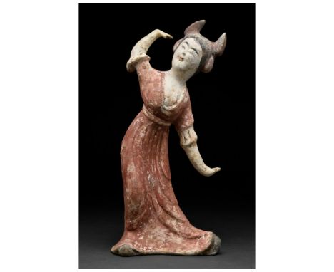 Ca. 618-907. Tang Dynasty. A delicate terracotta female dancer figure wearing a long flowing, deep orange gown with short sle