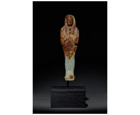 Ca. 664-332 BC. Late Period. A pale blue-glazed faience shabti on a modern stand, with a reddish-brown colouring over the upp