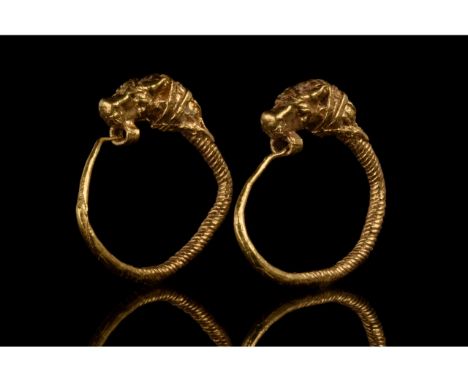 Ca. 300-100 BC. Hellenistic. A matched pair of ancient Greek gold earrings with hoops made of coiled wires; the lion-mask fin