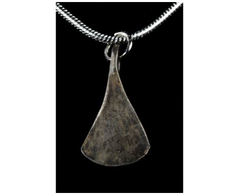 Ca. 700-900 AD. Northern Europe. A beautiful silver pendant with an integral loop shaped like a bearded Viking axe head. Good