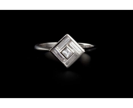 AN ART DECO STYLE DIAMOND PANEL RING, the square panel centred with a step-cut diamond in raised collet setting, framed by a 