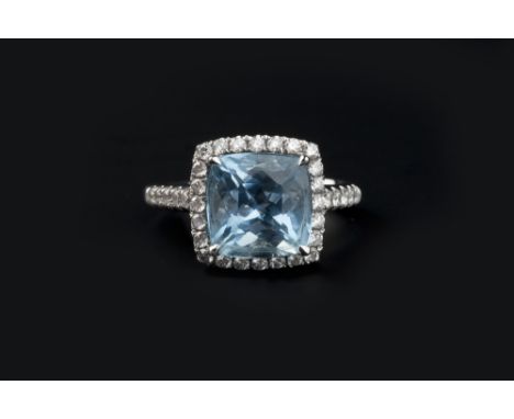 AN AQUAMARINE AND DIAMOND CLUSTER RING, the cushion-shaped mixed-cut aquamarine claw set within a border of round brilliant-c