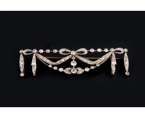 A DIAMOND SET PANEL BROOCH, of garland design, the openwork panel centred with a ribbon bow between festoons and foliage, mil