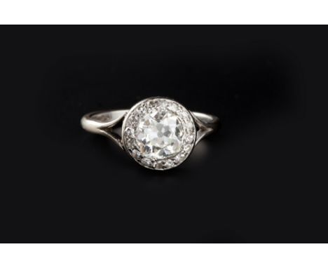 A DIAMOND PANEL RING, the principal cushion-shaped old-cut diamond framed by a border of smaller single-cut diamonds, between