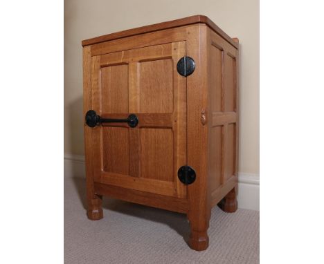 Workshop of Robert Mouseman Thompson (Kilburn): An English Oak Panelled Bedside Cupboard, with raised upstand, above a single