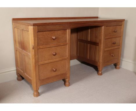 Workshop of Robert Mouseman Thompson (Kilburn): An English Oak Panelled Kneehole Dressing Table/Desk, with raised upstand abo