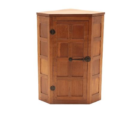 Workshop of Robert Mouseman Thompson (Kilburn): An English Oak Hanging Corner Cupboard, circa 1980, with panelled door enclos