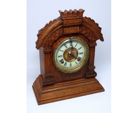 AMERICAN ANSONIA TUNIS SHELF CLOCK WITH A CIRCULAR DIAL ENCLOSING AN EIGHT DAY STRIKING MOVEMENT, IN A CARVED OAK CASE (H. 35