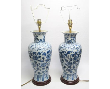 A PAIR OF CERAMIC TABLE LAMPS WITH BLUE AND WHITE DECORATION ON A TURNED WOOD BASE (H. 46 CM). 