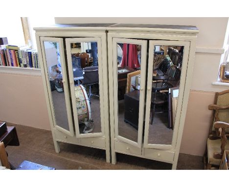 A Pair of Matching White Painted Wardrobes. The wardrobes having mirrored front doors, two short drawers beneath, one with in