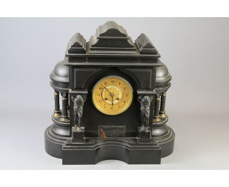 A Victorian Slate Mantel Clock. The clock with gilt-brass face and numeric dial, flanked by a part dome with three columns an