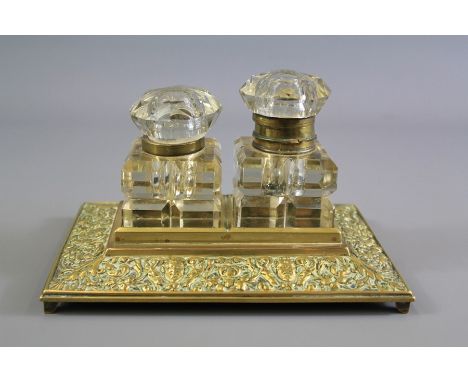 A Victorian Brass Double Inkwell. The inkwell with two square cut-glass ink bottles, the hinges are broken but intact, with f