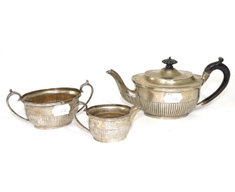 A late Victorian silver bachelor's three piece tea service, London 1893, of semi-fluted ovoid form, engraved with an initial,