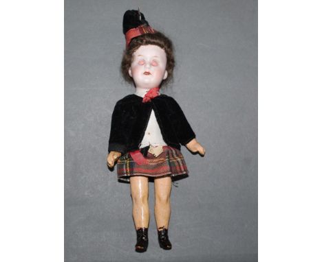 An early 20thC German Carl Hartmann "Globe Baby" doll, having a bisque head and composition limbs, wearing traditional Scotti