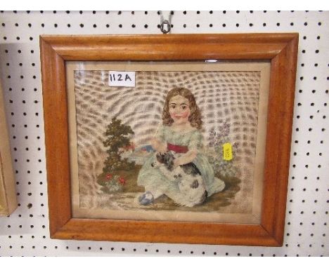 A 19th century framed tapestry picture of a seated girl with a dog on her lap, in a birdseye maple frame
