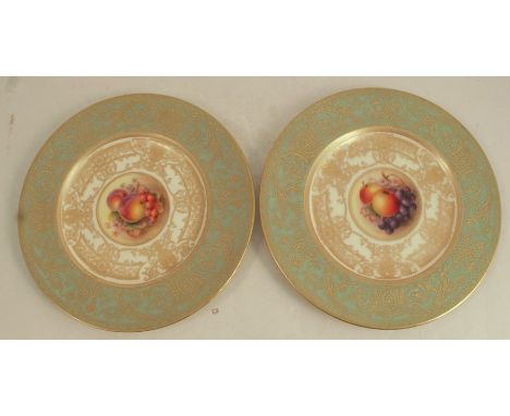 A pair of Royal Worcester plates, decorated with a central panel of hand painted fruit by W Bee, to a richly gilt deep ivory 