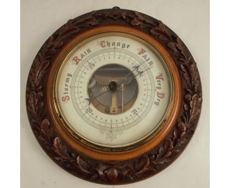 A wall barometer, of circular form, having a carved frame decorated with acorns and oak leaves, overall diameter 12.5ins