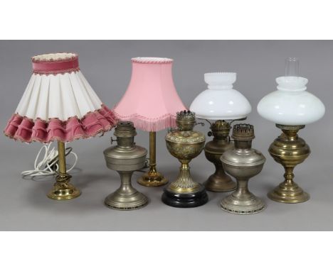 An Edwardian brass embossed oil table lamp, 21¾” high; together with four other oil lamps; &amp; a pair of brass table lamps,