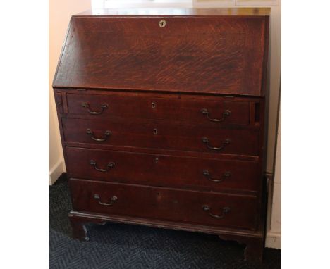 A 19th century oak bureau with fitted interior enclosed by fall-front above four long graduated drawers with brass swing hand