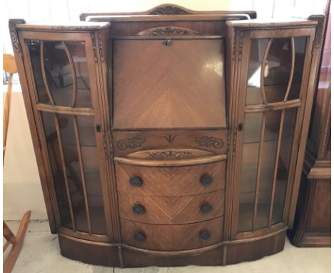 A vintage light wood bow fronted sideboard with carved detail to front. Has 3 central drawers, 2 glass doors with interior gl