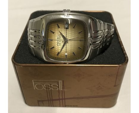 A Mens wrist watch by Fossil. Stainless steel bracelet, square face with brown coloured dial. Date feature and water resistan