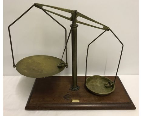 A set of brass shop weighing scales on a wooden plinth. By Sangers Shopfitters 258 Euston Road. N.W. 